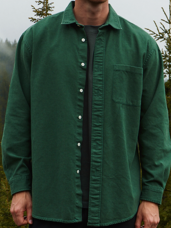 Man wearing a deep forest green heavyweight brushed cotton flannel shirt in a misty forest